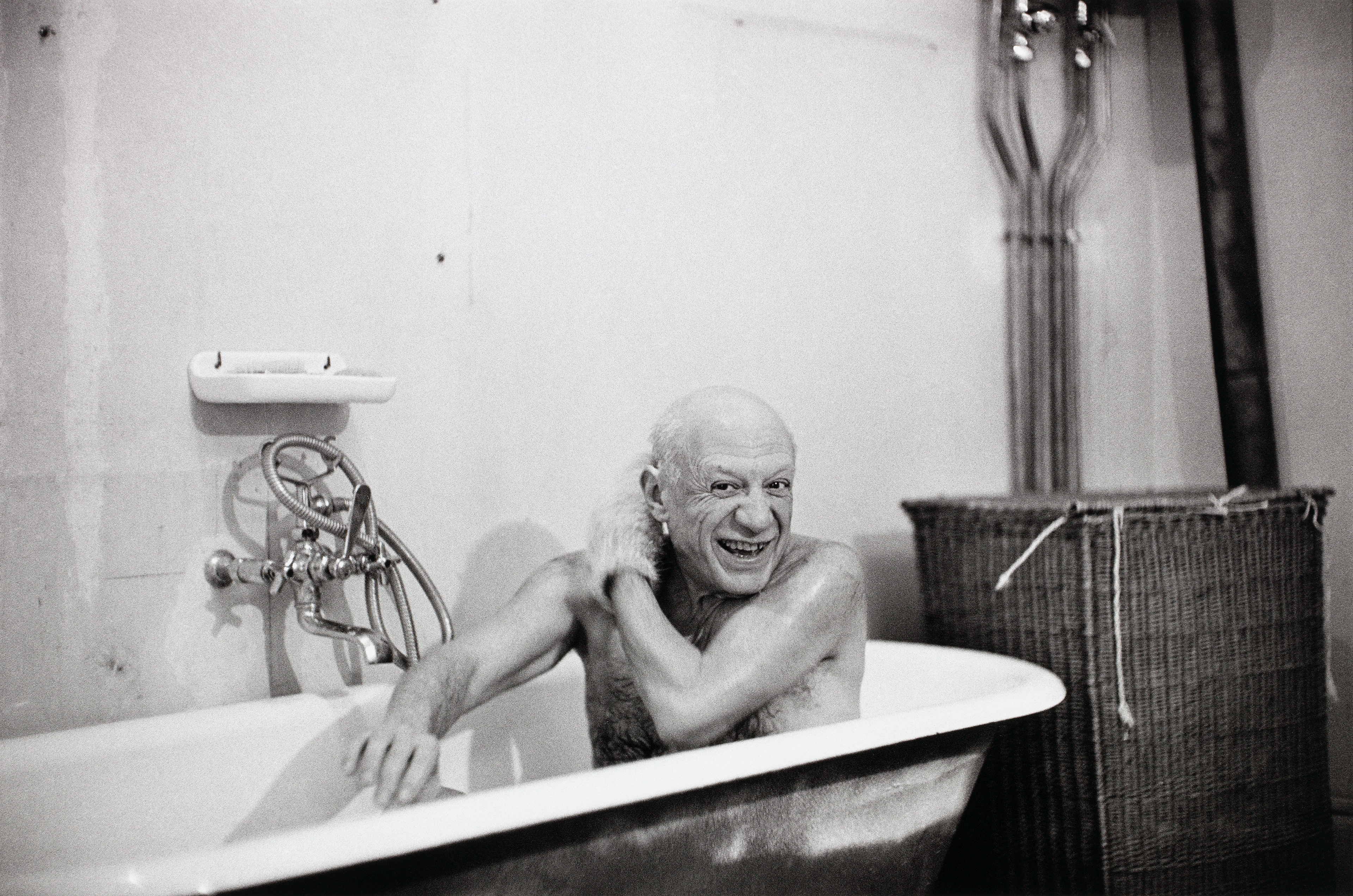 Imagen en blanco y negro, el artista Picasso sentado contento en una bañera