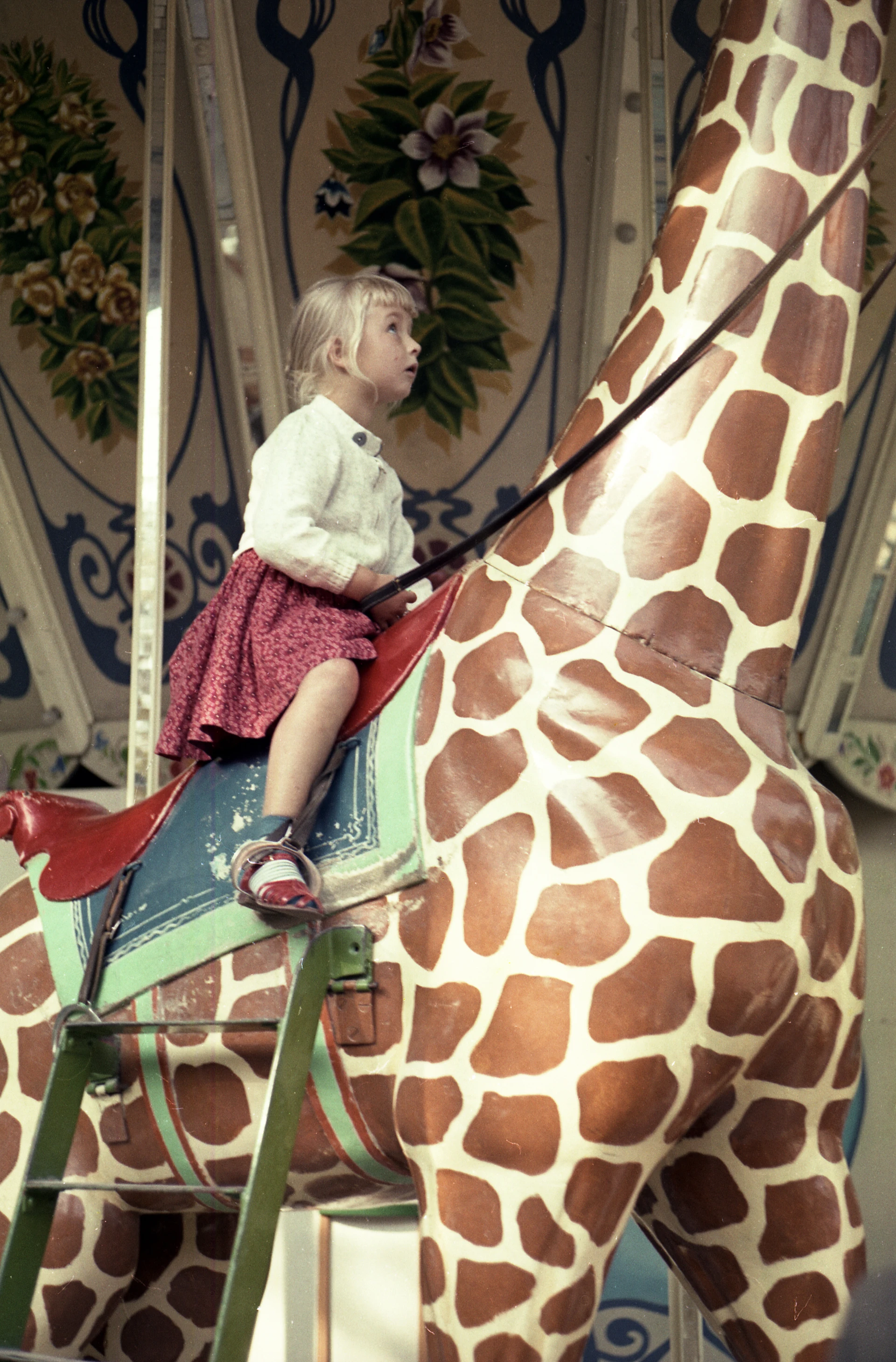 Niña pequeña sentada en una jirafa en un carrusel
