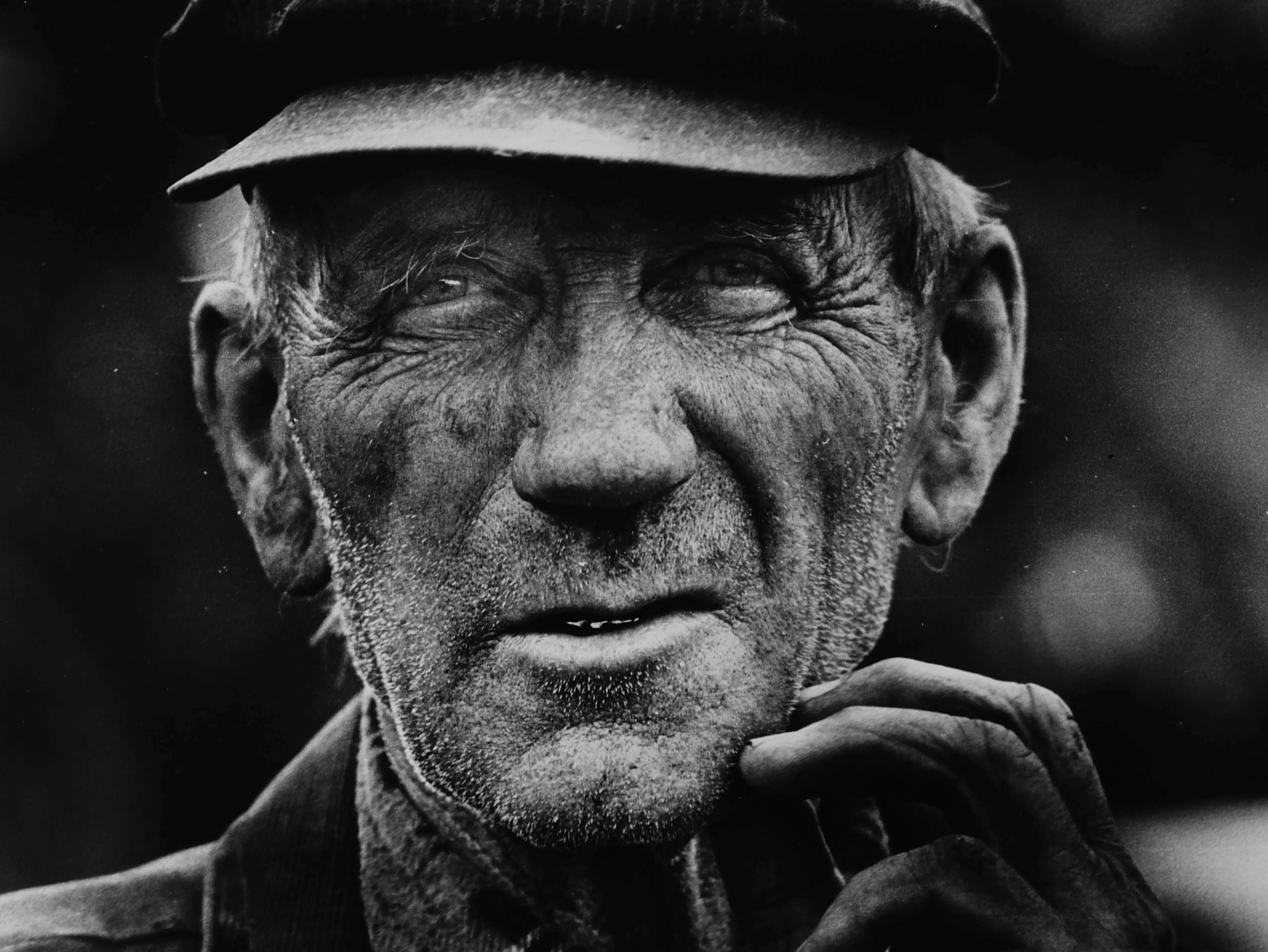 Ritratto in bianco e nero di un anziano contadino con cappello e sguardo risoluto.