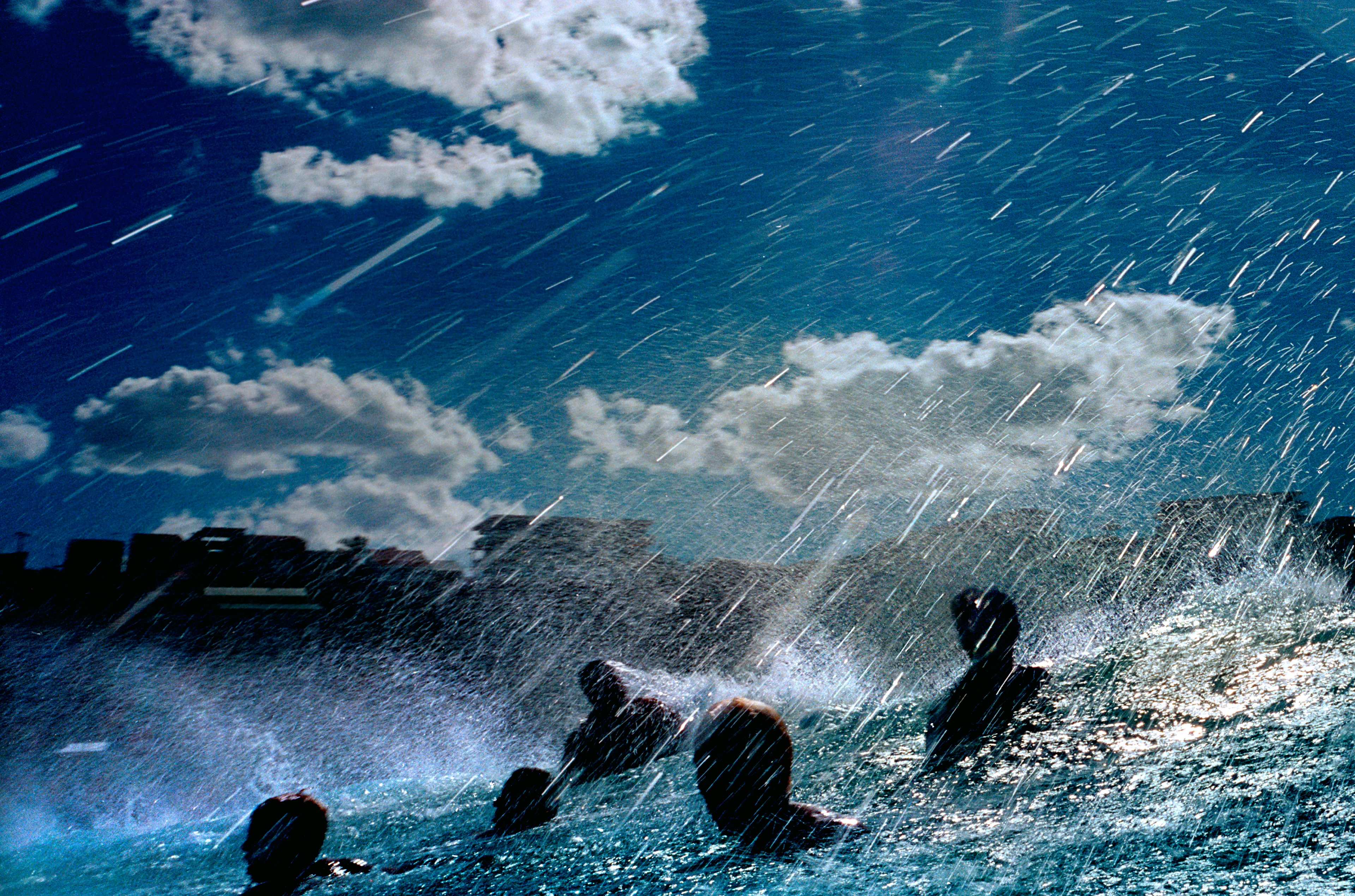 近乎神秘的照片，幾名男子在海中游泳，水花在陽光下四濺。