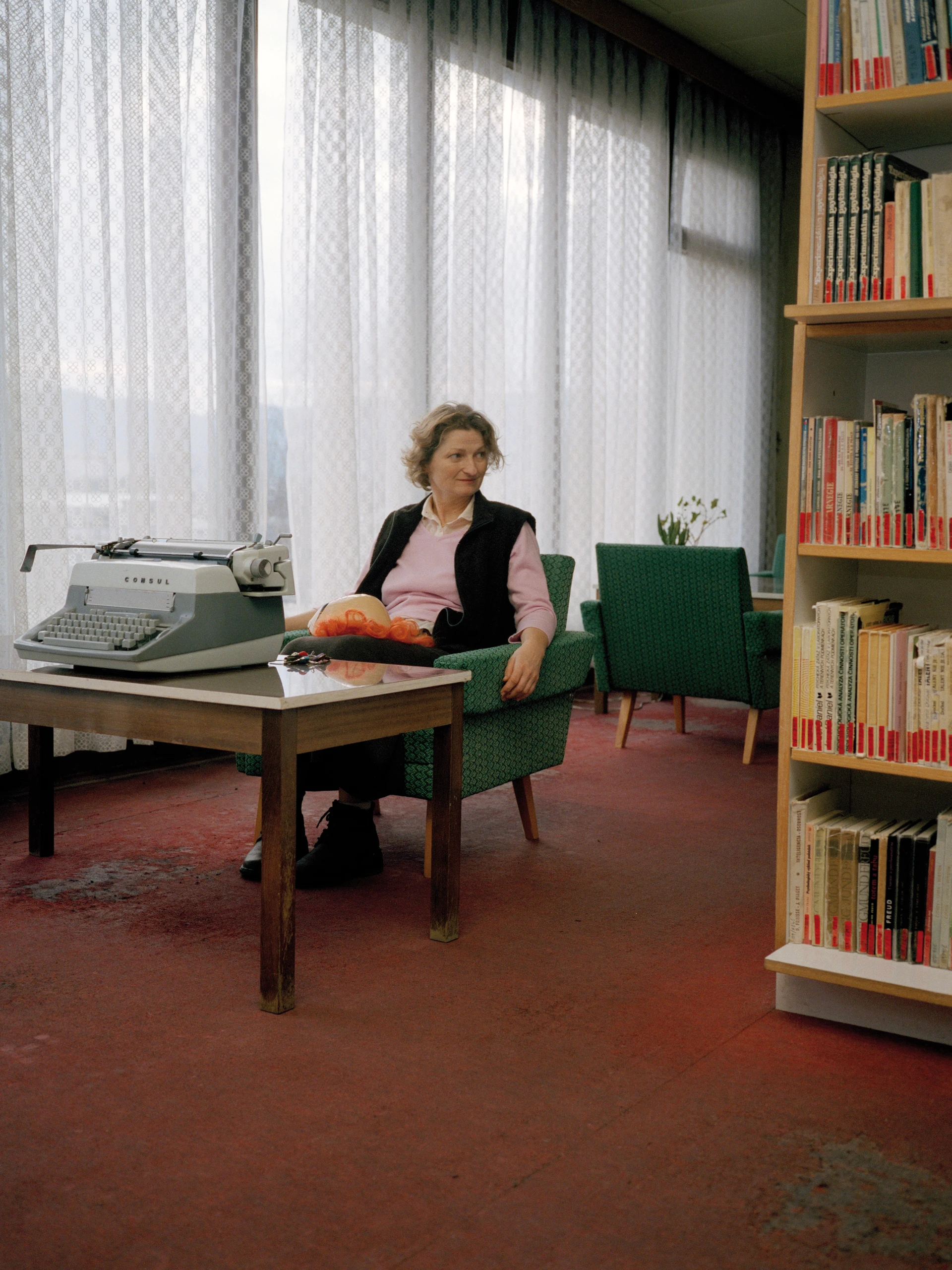 圖書館內，一位女士坐在70年代風格的單人椅上，面前擺著一台老式打字機。
