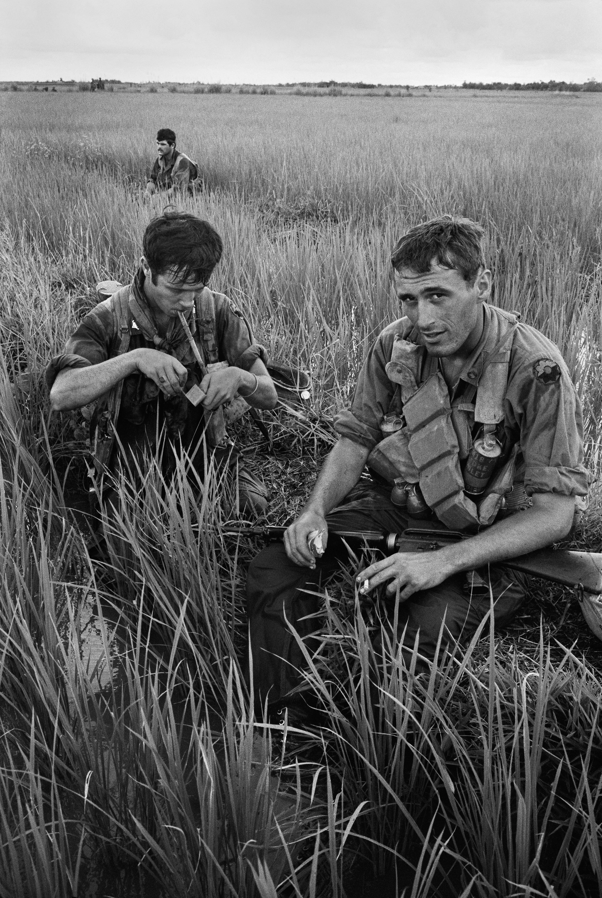 Motyw czarno-biały, wojna w Wietnamie, dwóch żołnierzy odpoczywa na polu i pali papierosy