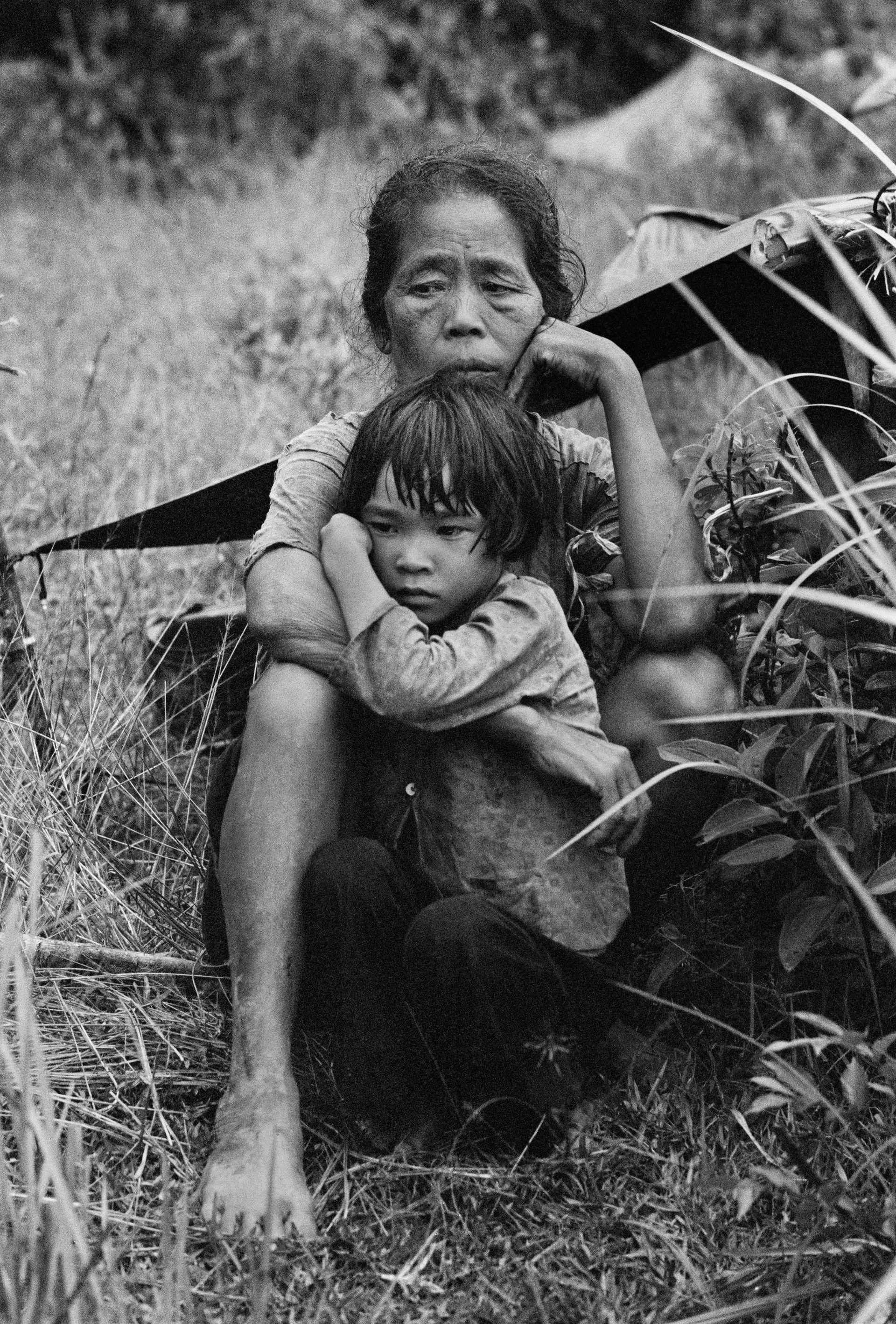 Motyw czarno-biały, wojna w Wietnamie, wietnamska matka siedzi na polu i trzyma w ramionach dziecko