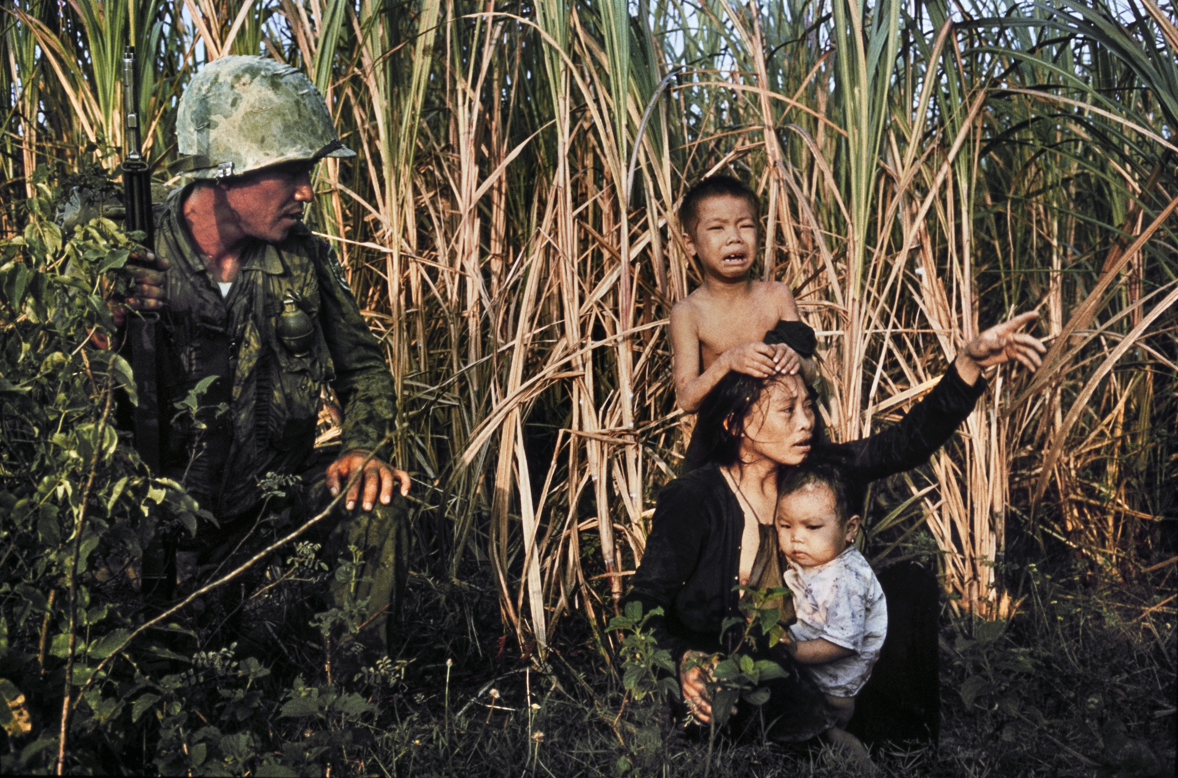 Wojna w Wietnamie, żołnierz klęczy obok Wietnamki z płaczącymi dziećmi