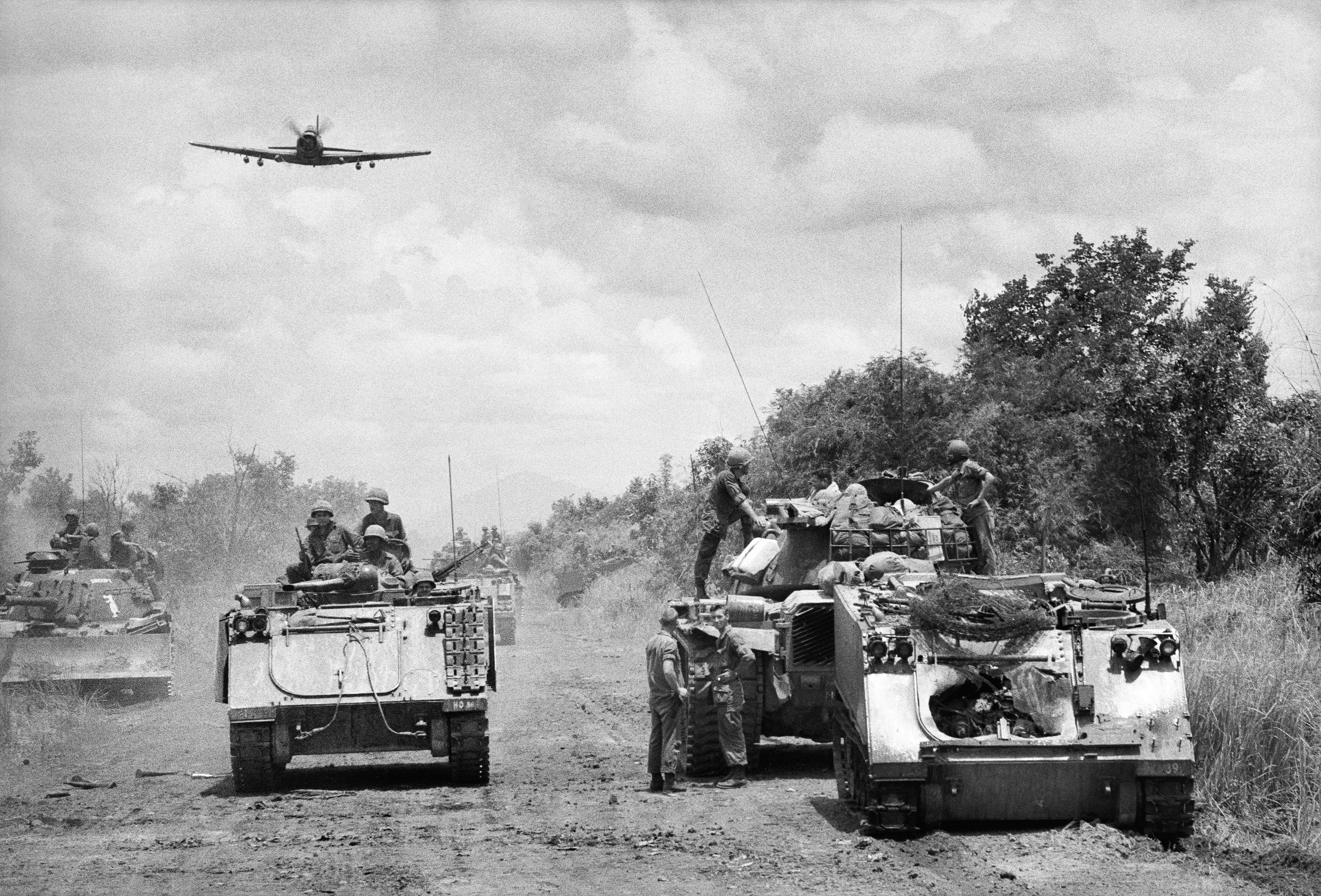 Motyw czarno-biały, wojna w Wietnamie, czołg i żołnierze na drodze, samolot w powietrzu