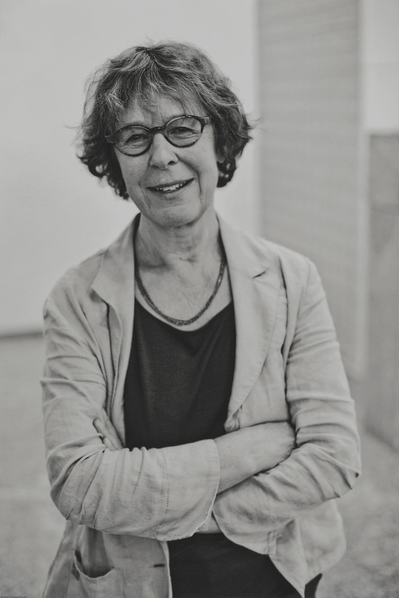 芭芭拉·克莱姆的黑白肖像,她穿着西装外套,双臂交叉,对着相机镜头微笑。