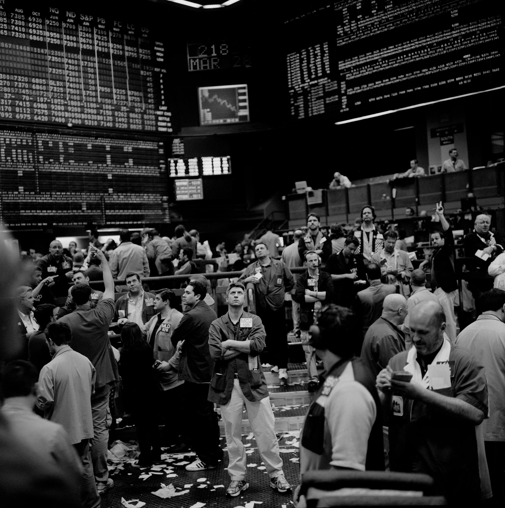 Czarno-białe zdjęcie zgiełku na nowojorskiej giełdzie papierów wartościowych z dziesiątkami rozczarowanych sprzedawców patrzących w górę.