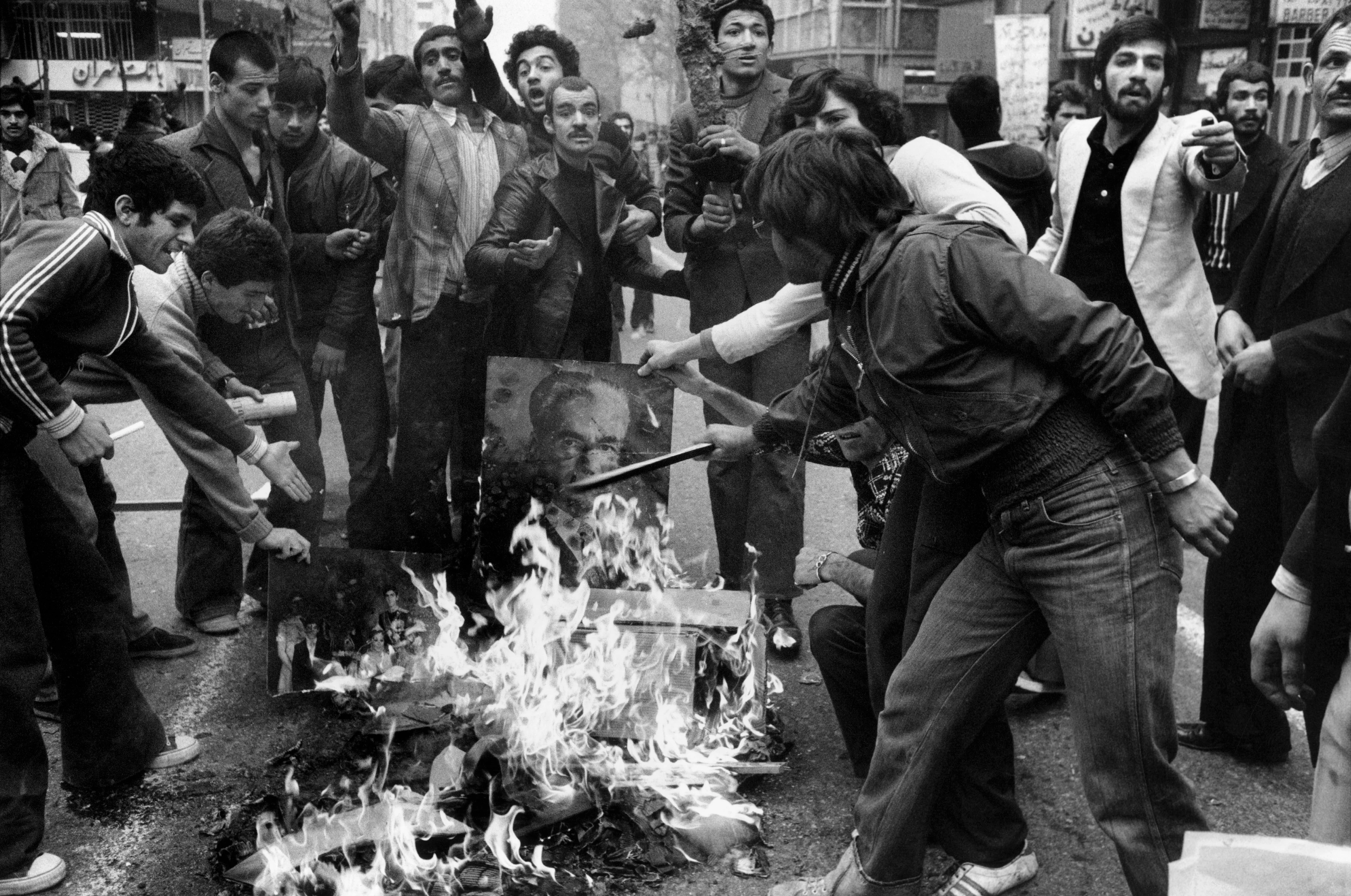 Imagen en blanco y negro, manifestantes furiosos queman imágenes en la calle
