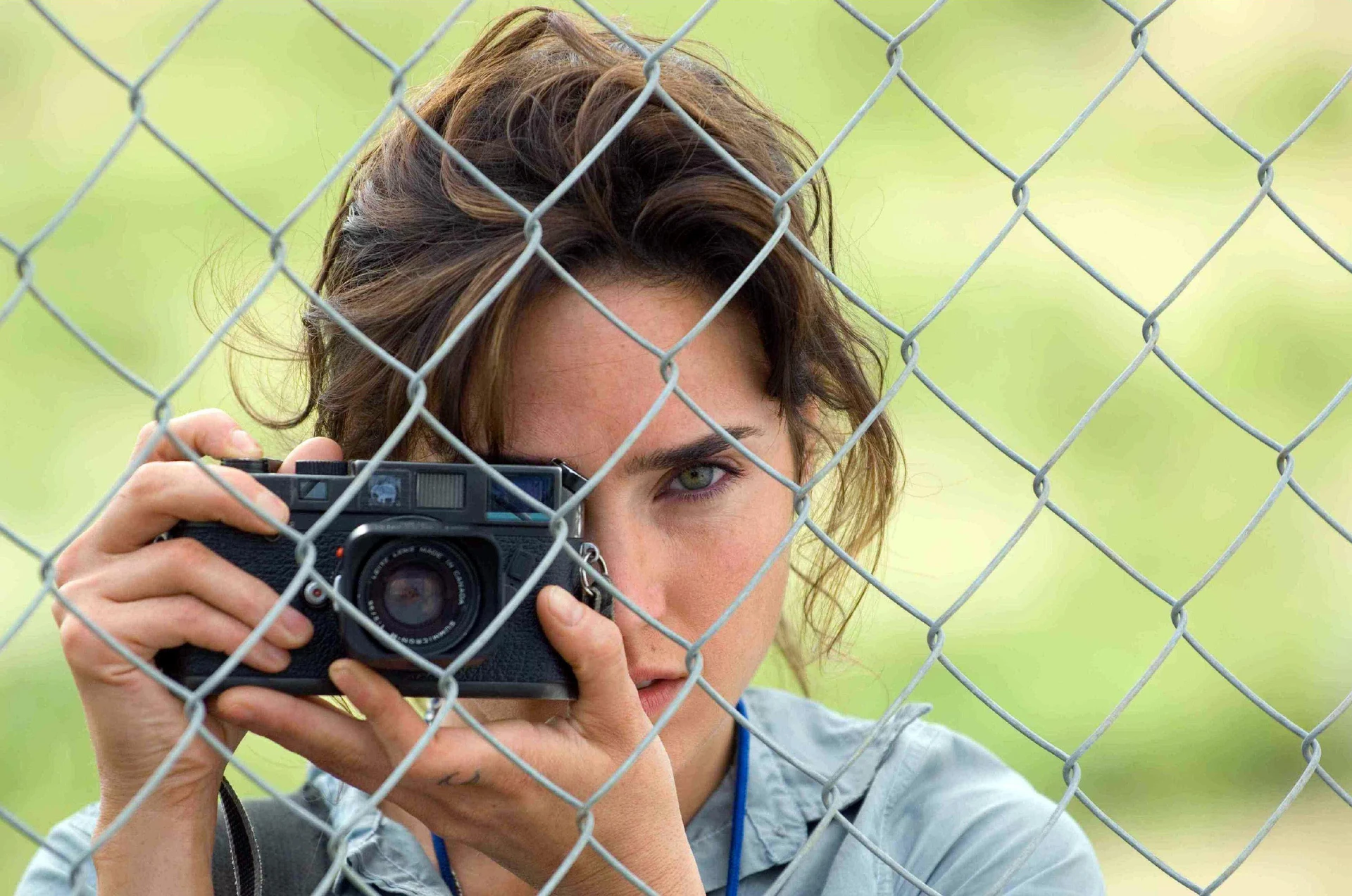 Jennifer Connelly z aparatem Leica M6 w scenie z filmu Blood Diamond, otoczona innymi fotografami i kamerzystami.