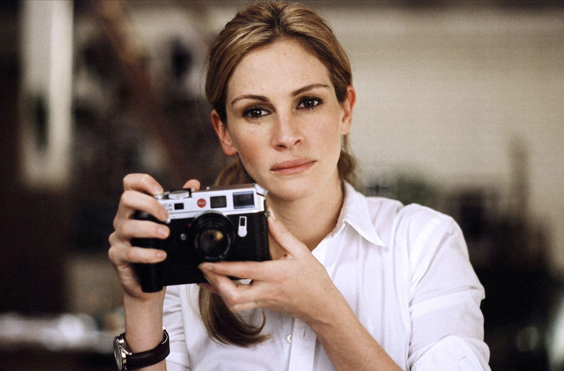 Julia Roberts patrzy w obiektyw aparatu podczas kręcenia sceny do filmu Closer i trzyma w ręku aparat Leica R8.