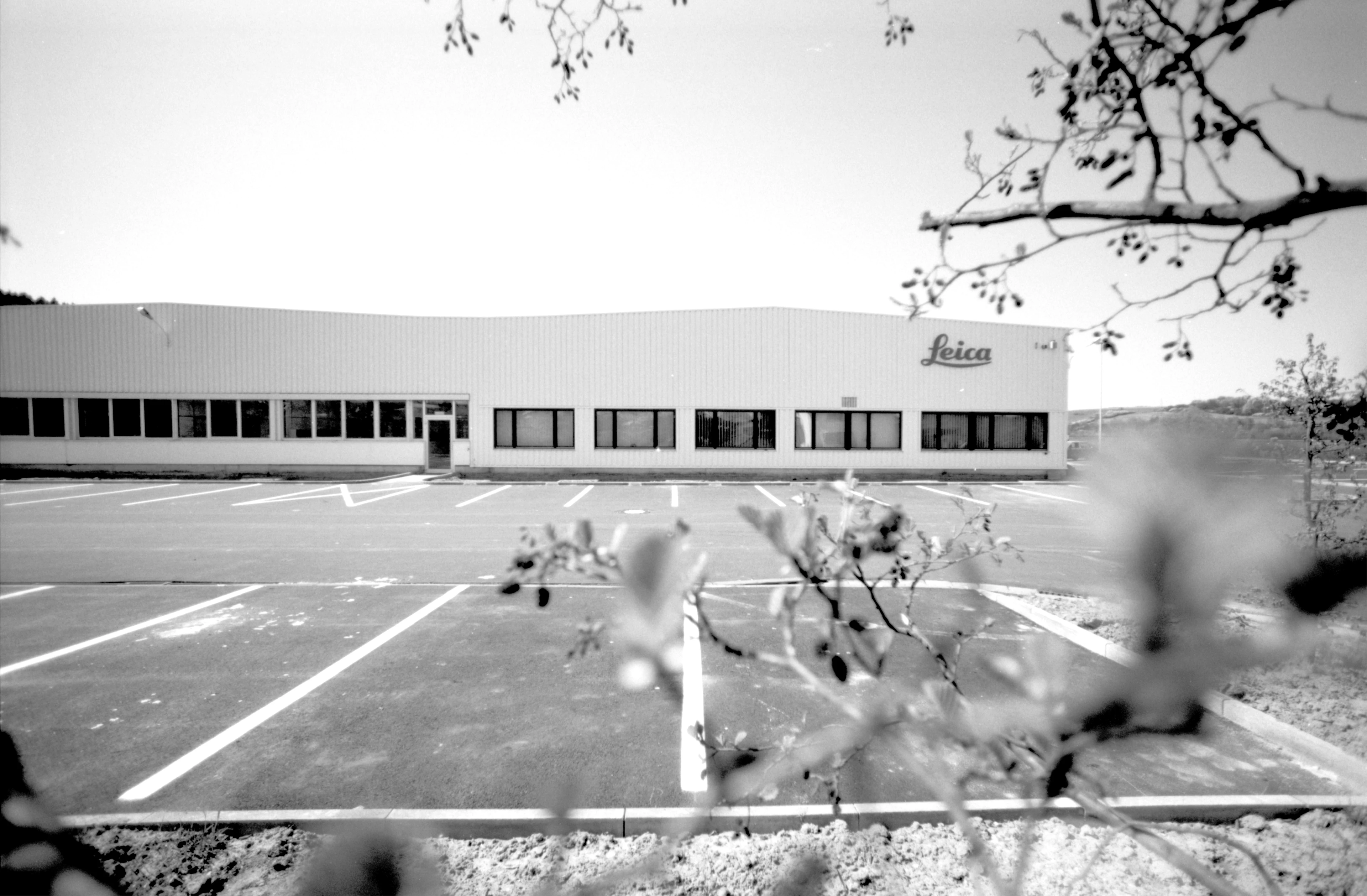 Foto in bianco e nero dello stabilimento Leica a Solms con il parcheggio antistante vuoto.