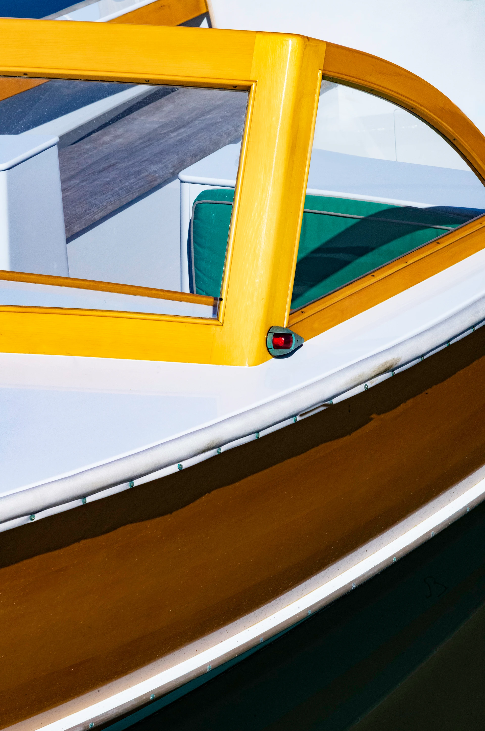 Close-up of a white motorboat with striking yellow window frames, green seat cushions and wooden panelling on the side.
