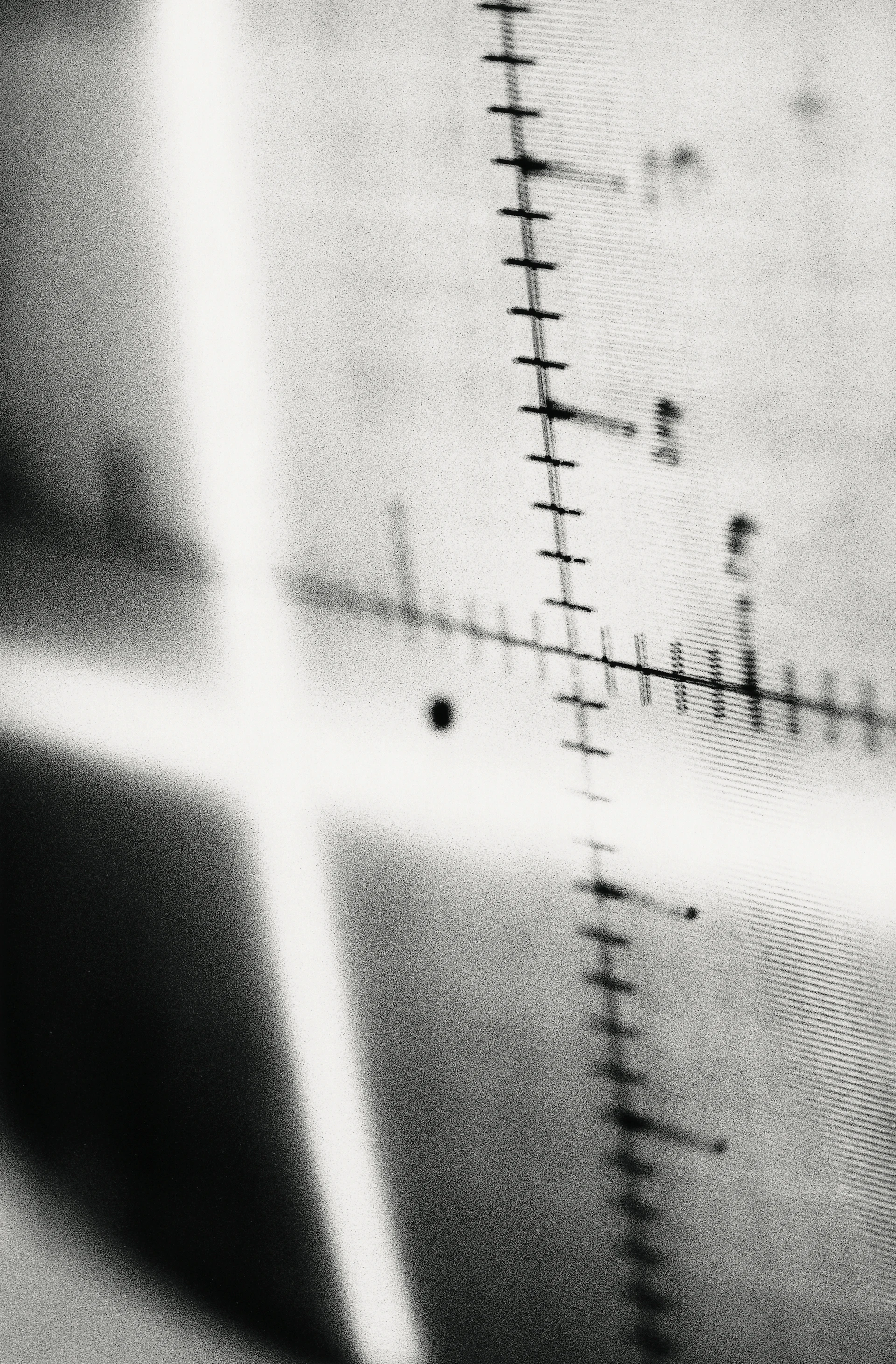 Primo piano astratto in bianco e nero di un fascio di luce a due assi su un campo di misura longitudinale incrociato.