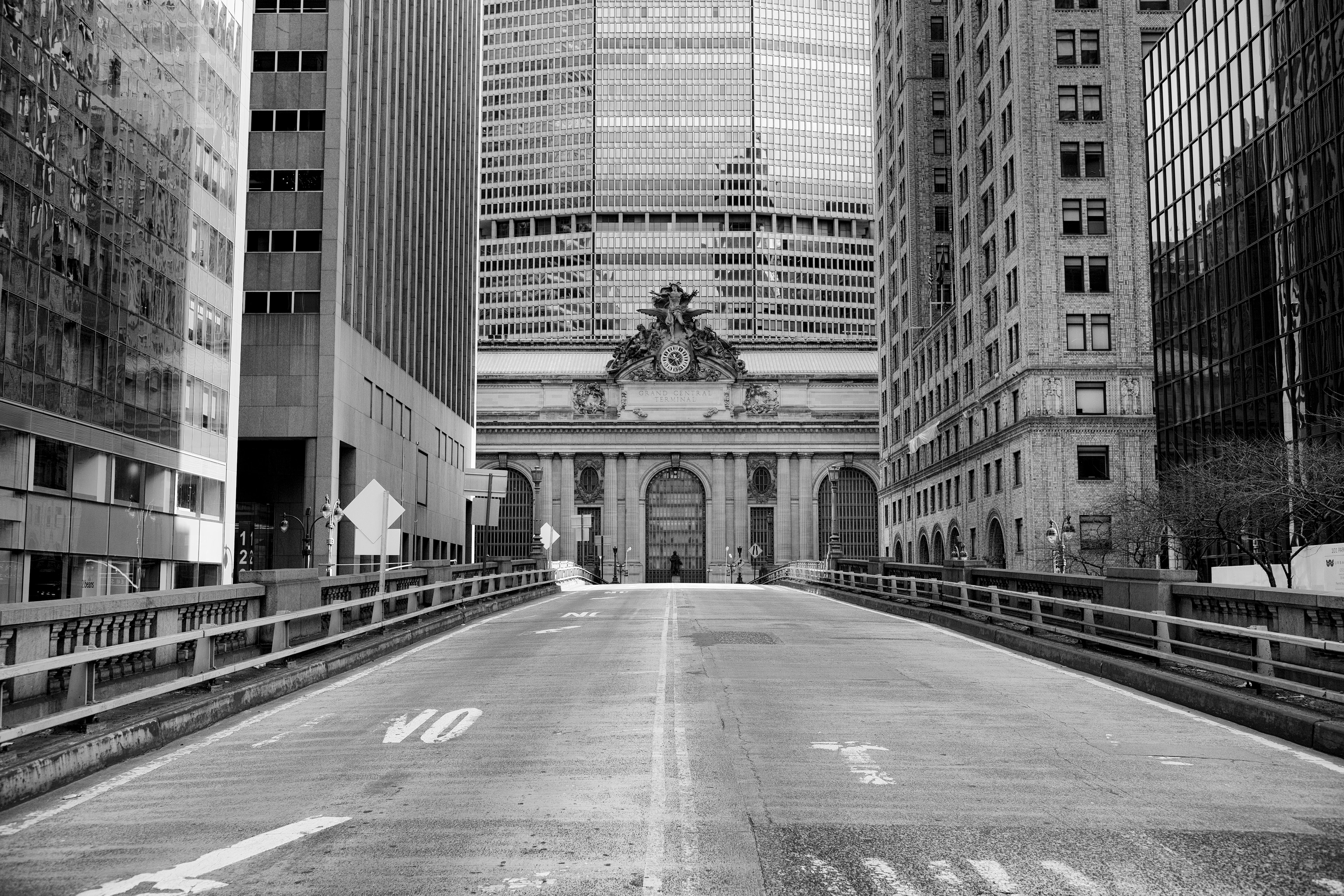 黑白照片：一条空无一人的宽阔街道，两旁高楼林立，中轴线上是大中央火车站。