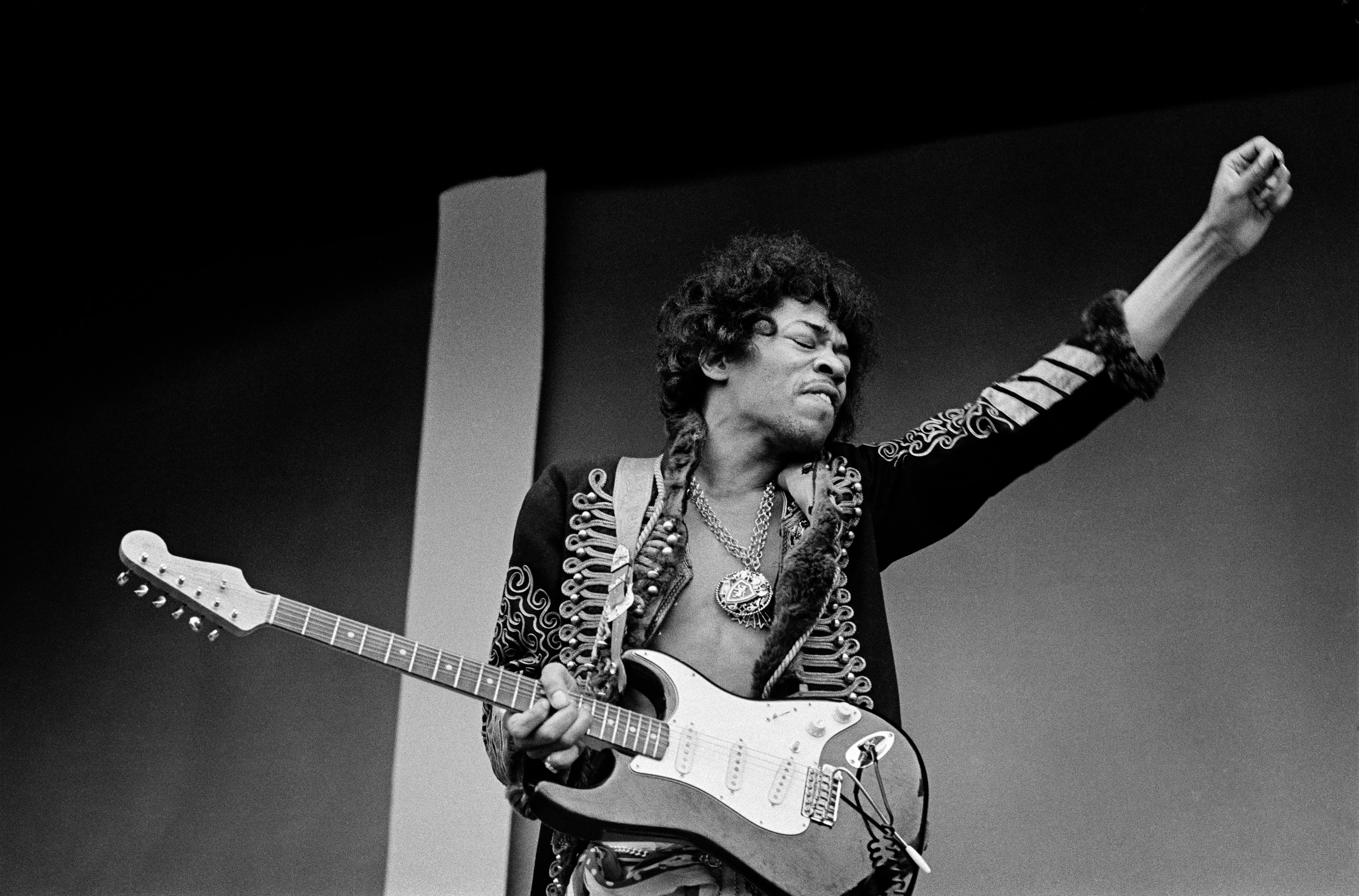 Black-and-white image of Jimi Hendrix playing the guitar with his arm outstretched and absorbed in the music