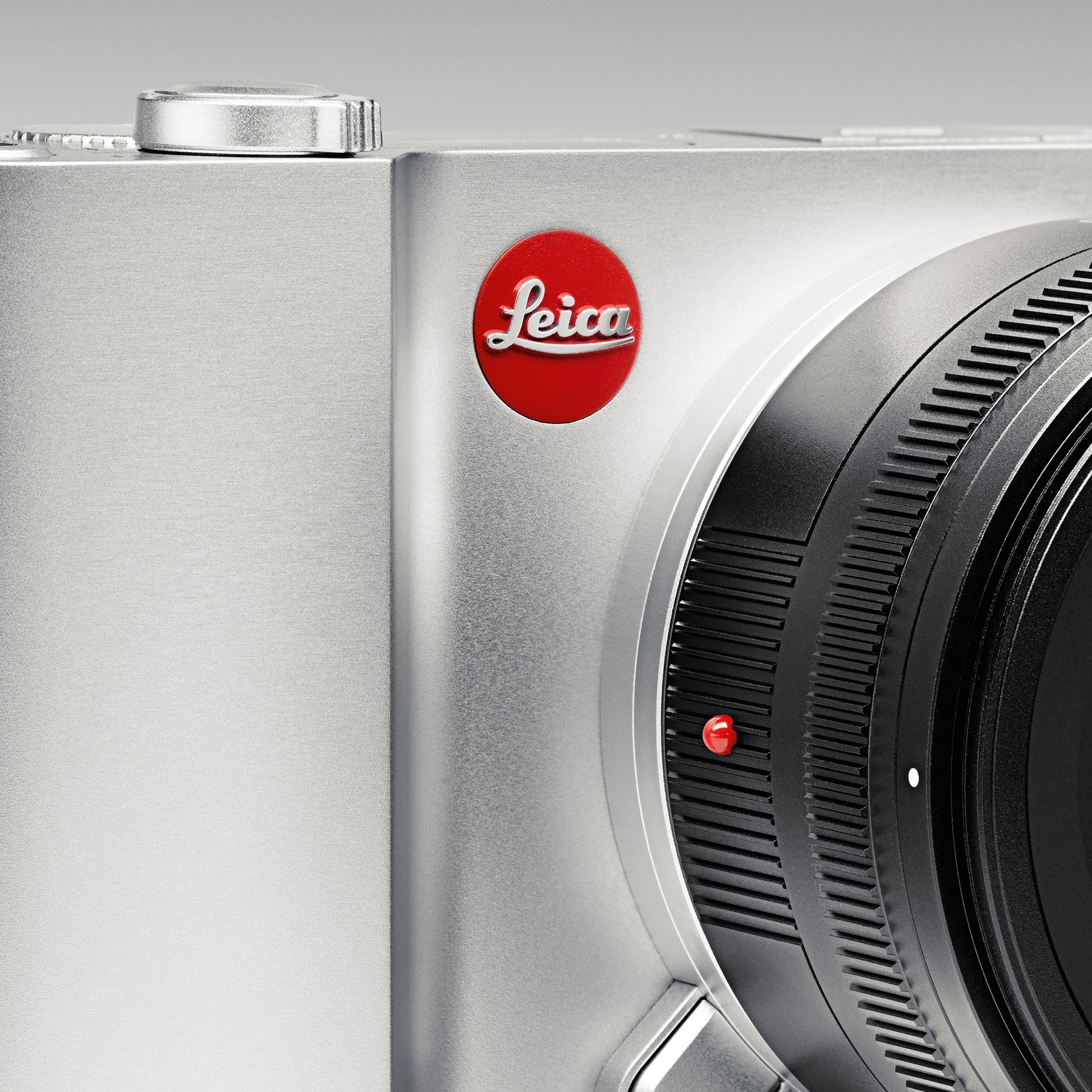 小型特写照片:徕卡T相机正面的局部特写,展示其光滑圆润的铝合金机身、开/关按钮、徕卡标志和部分镜头。