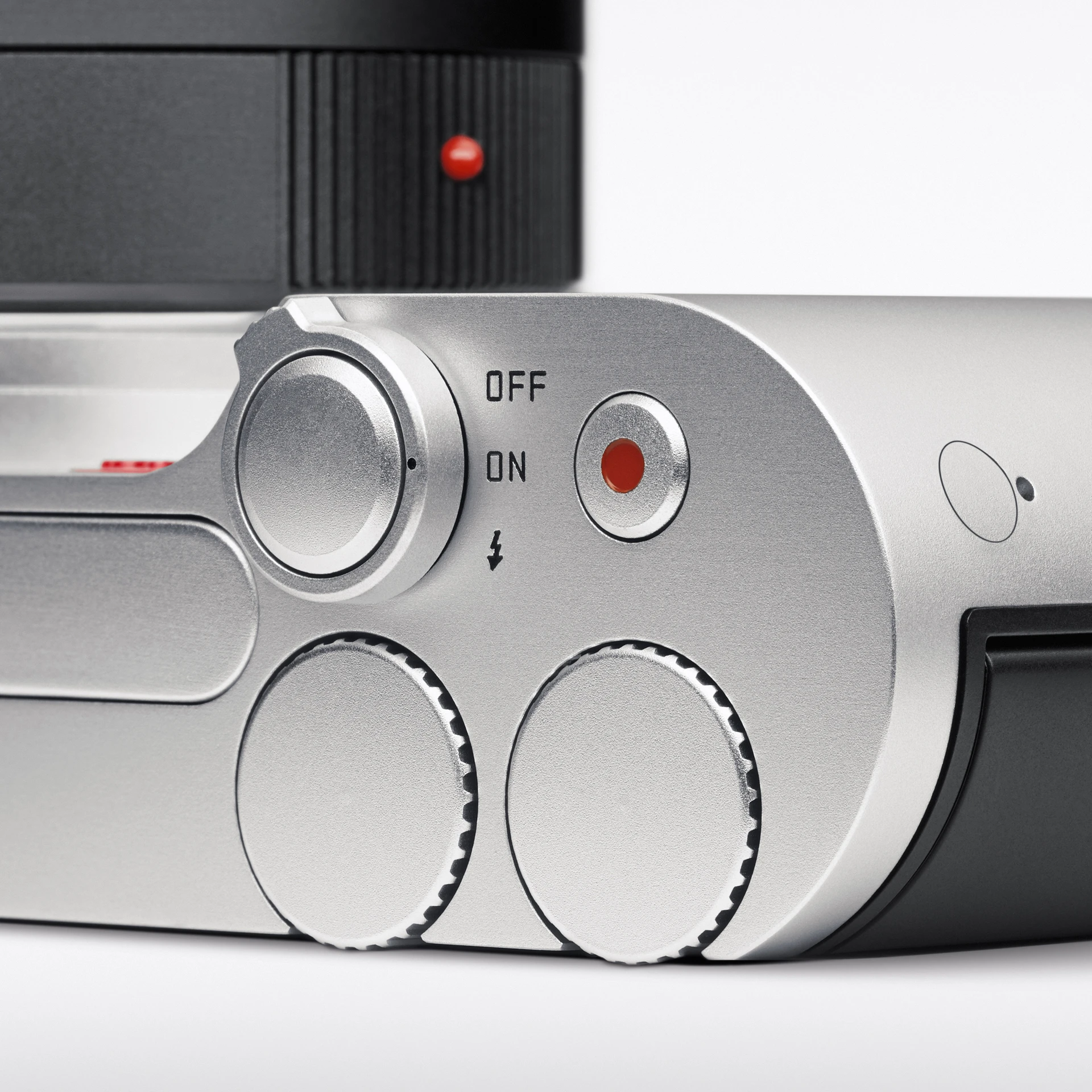 小型特写照片:徕卡T相机侧面的局部特写,有带凹槽的设置旋钮、开/关按钮和银色铝合金机身上的圆形红色快门按钮。