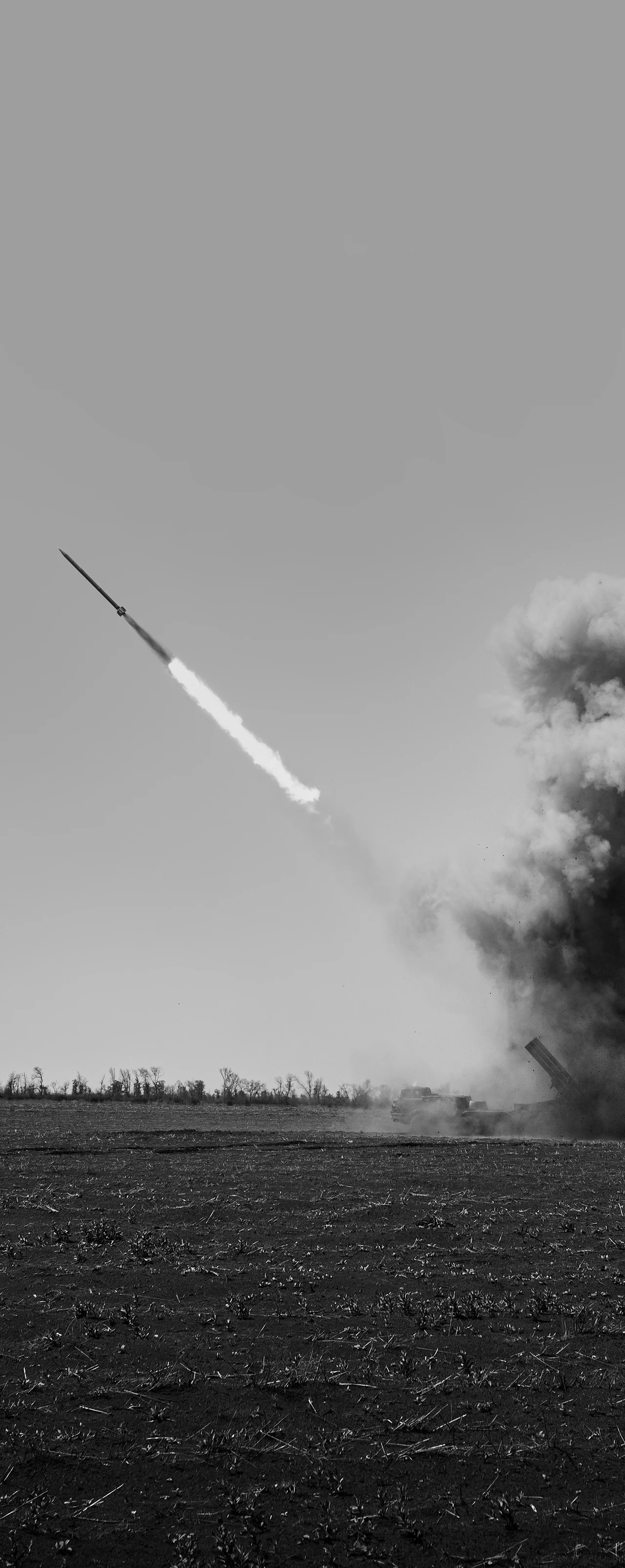 Schwarz-Weiß-Bild: Eine Kampfrakete fliegt von einem flachen Feld ab und hinterlässt eine gewaltige dunkle Rauch- und Staubwolke, die senkrecht in den Himmel steigt.