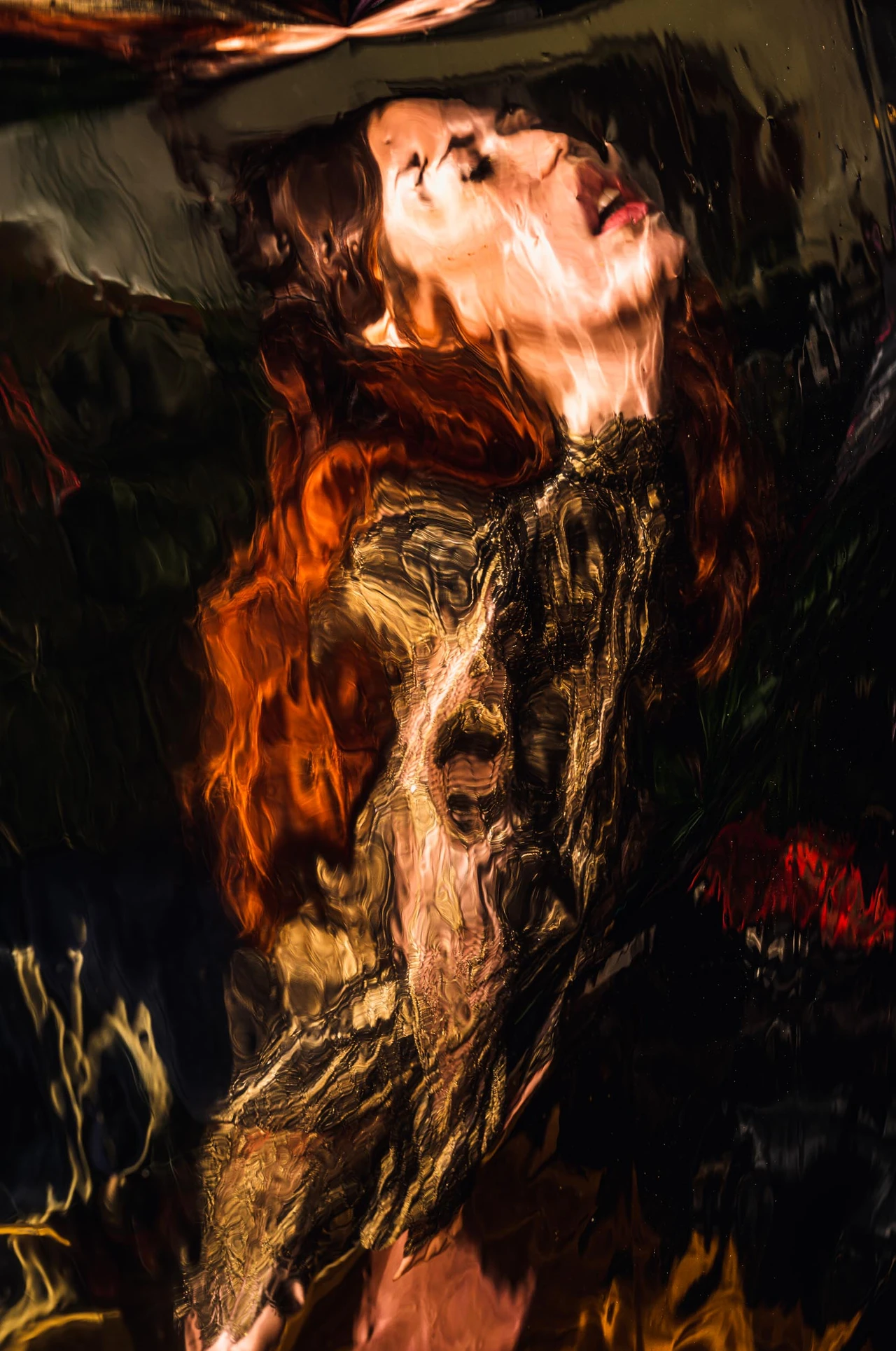 A highly distorted, abstract-looking portrait of a woman with her head tilted back and auburn hair fills the picture, as if seen through an unevenly reflective or fluid surface.