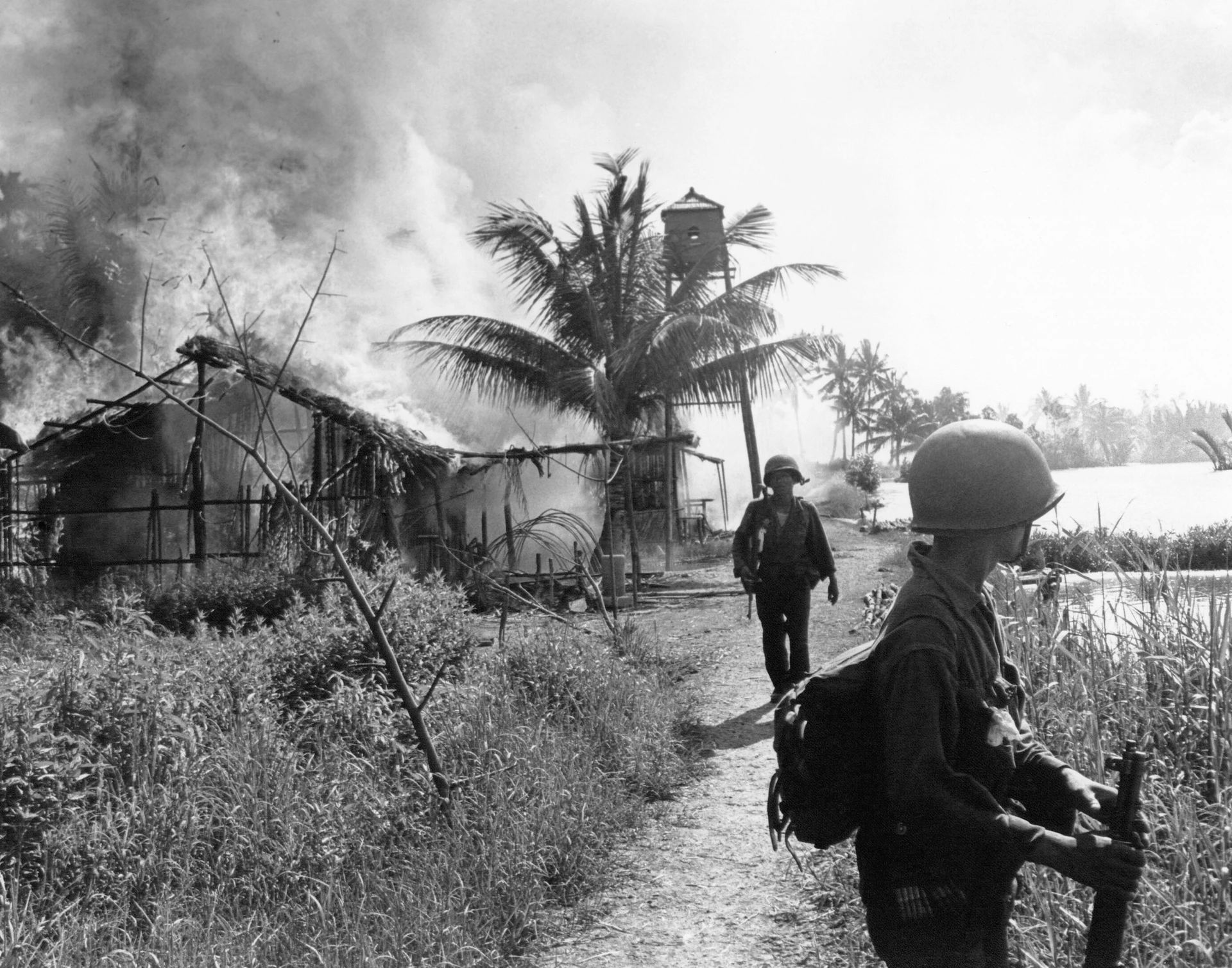 Motyw czarno-biały, wojna w Wietnamie, dwóch żołnierzy, w tle dym na niebie